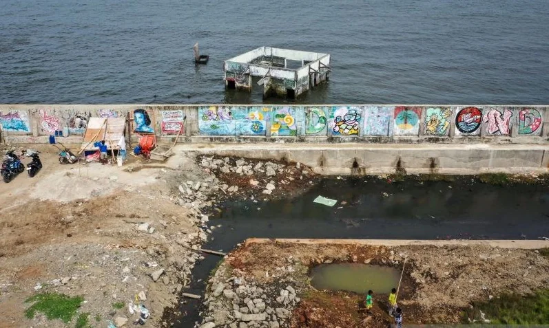 Dokumentasi - Foto udara anak-anak bermain di area tanggul laut dan masjid yang terendam air laut di Muara Baru, Penjaringan, Jakarta, Kamis (8/1/2026). Badan Riset dan Inovasi Nasional (BRIN) mencatat rata-rata penurunan tanah di Jakarta bagian utara ter