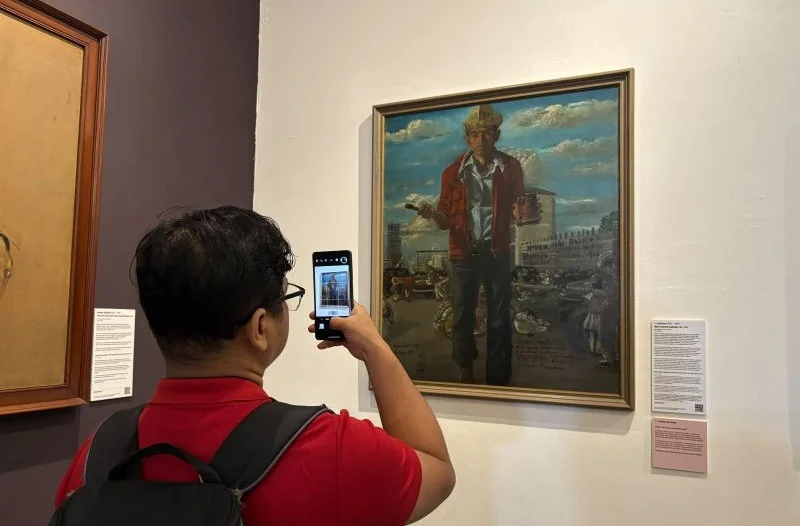 Seorang pengunjung memotret lukisan berjudul "Maka Lahirlah Angkatan 66" karya S. Sudjojono, dalam pameran “The Adam Malik Collection" di Museum Seni Rupa dan Keramik (MSRK) Jakarta, Kamis (20/8/2026). Pameran ini diadakan pada 15-23 Agustus 2026. Foto: A