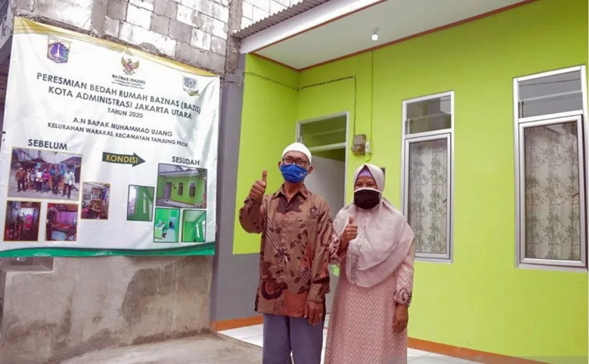 Muhammad Ujang (63) warga Jalan Warakas V Gang I, Kecamatan Tanjung Priok, Jakarta Utara, berfoto bersama istrinya di depan rumahnya yang selesai dibedah lewat program bedah rumah Baznas (Bazis) DKI Jakarta, Minggu (17/1/2021). Foto: Kominfotik Jakarta Ut
