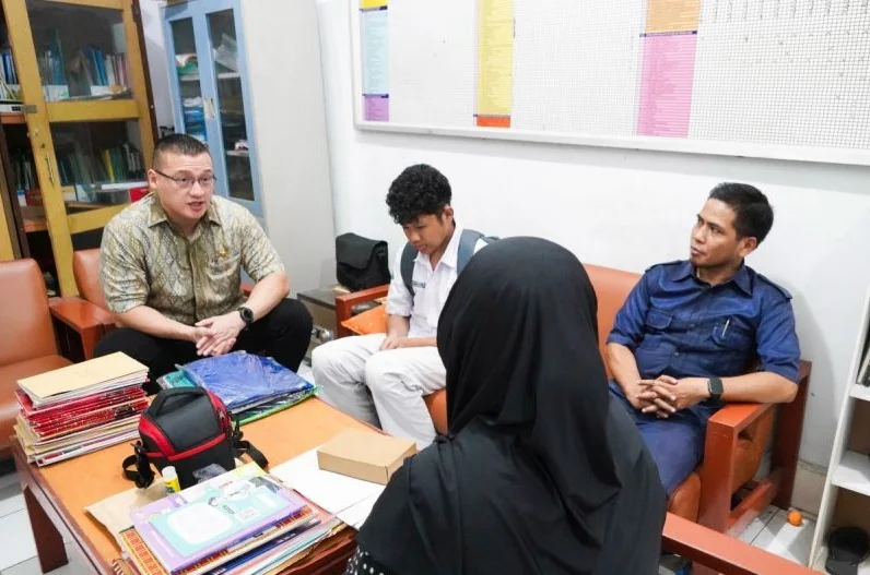 Anggota DPRD DKI Jakarta Hardiyanto Kenneth (kiri) memberikan bantuan kepada seorang siswa yang kesulitan membayar uang sekolah dan seragam. Foto: ANTARA